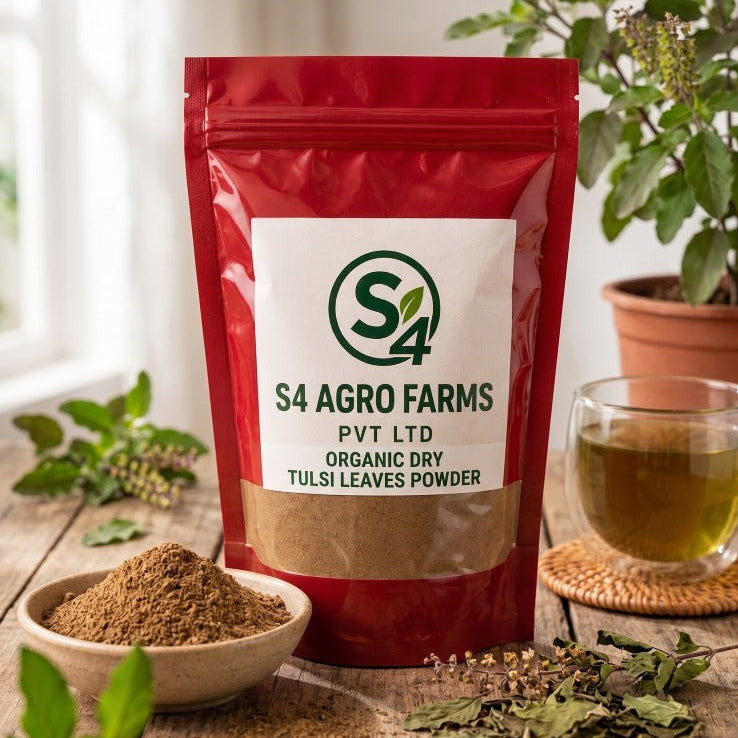 Red package of S4 Agro Farms Tulsi leaves powder on a wooden surface with a glass of tea and herbs.