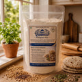A stand-up pouch of Torte Living Nutri Sampoon Multigrain Atta flour, placed on a wooden surface with loose grains, seeds, and flatbread around it. The pouch is centered and clearly shows the front label with product details.
